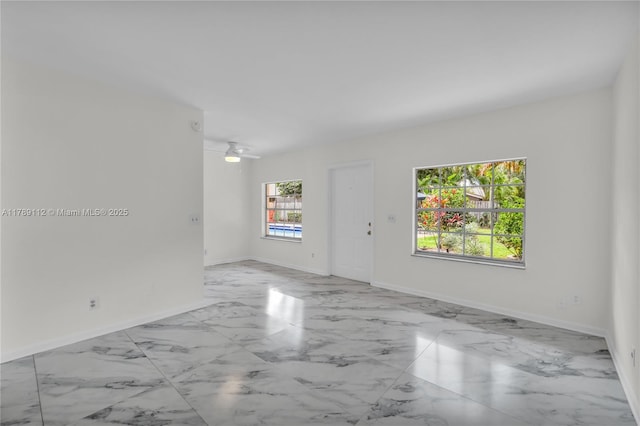 empty room with baseboards, a ceiling fan, and marble finish floor