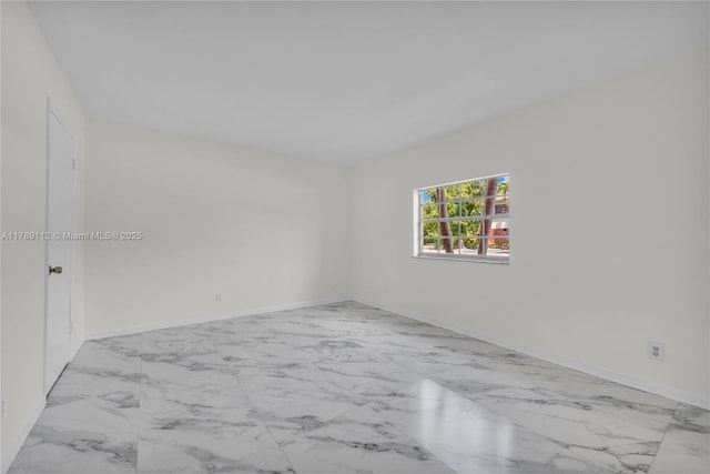 empty room featuring baseboards and marble finish floor