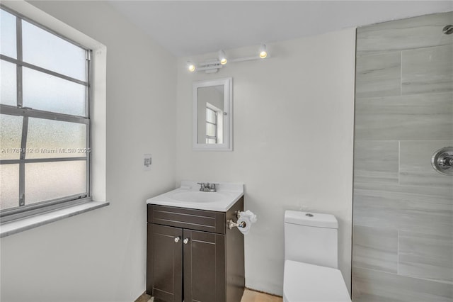 full bath featuring a tile shower, toilet, and vanity