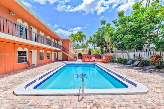 community pool with fence and a patio area