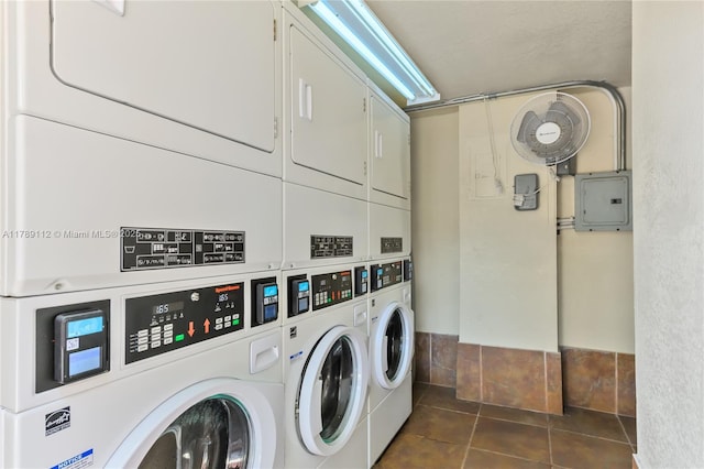 shared laundry area featuring dark tile patterned floors, stacked washer / dryer, electric panel, and washing machine and dryer