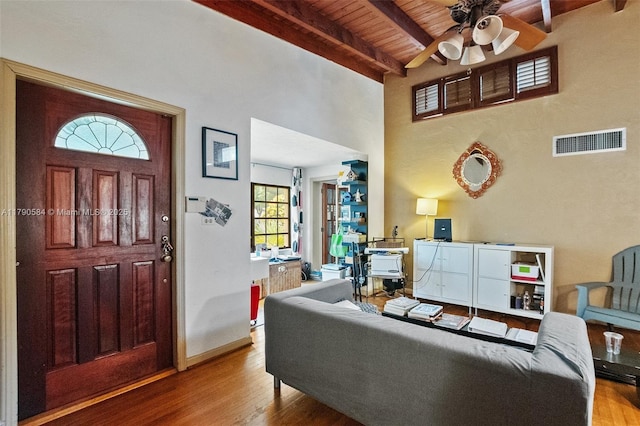 living area with beamed ceiling, a ceiling fan, visible vents, wood ceiling, and wood finished floors