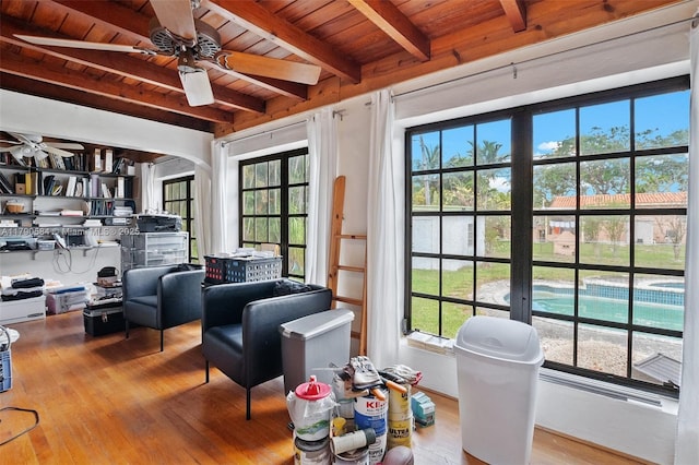 sitting room featuring wood ceiling, beamed ceiling, arched walkways, wood finished floors, and a ceiling fan