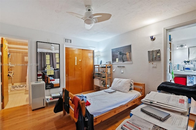bedroom featuring a textured ceiling, visible vents, connected bathroom, and light wood-style flooring