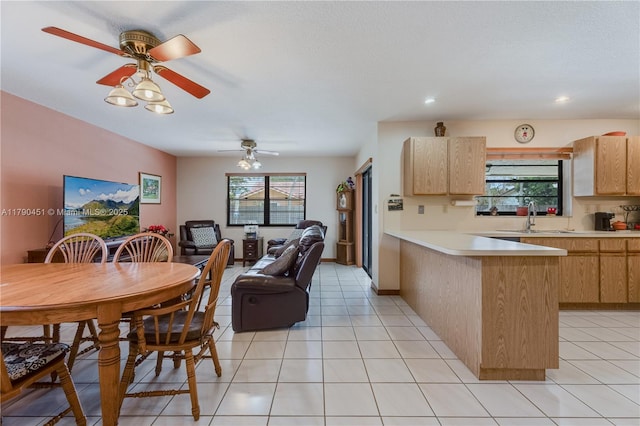kitchen featuring a peninsula, light brown cabinetry, light countertops, a sink, and open floor plan