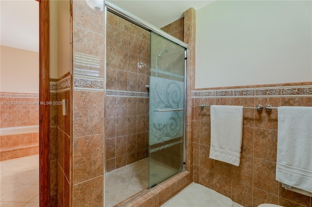 bathroom with tile walls, a shower stall, and wainscoting