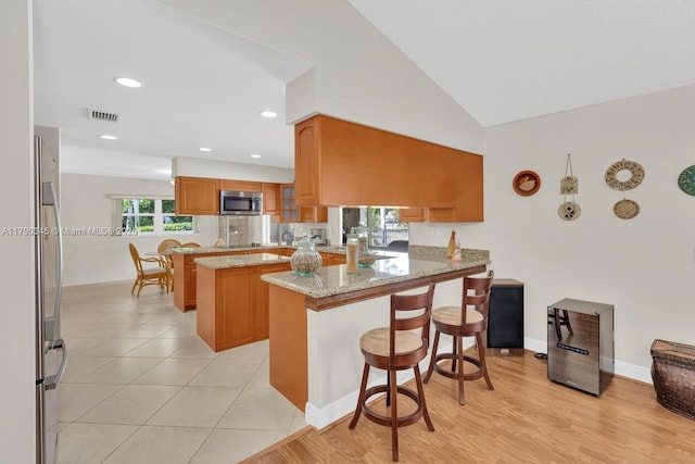 1800 NW 105th Ln, Coral Springs, FL 33071 - kitchen with light stone countertops, a breakfast bar, visible vents, a peninsula, and appliances with stainless steel finishes