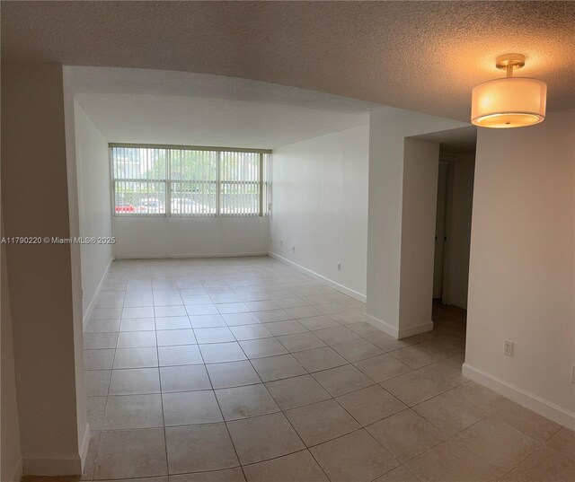 1420 Brickell Bay Dr Unit 103A1, Miami, FL 33131 - spare room featuring baseboards, light tile patterned floors, and a textured ceiling