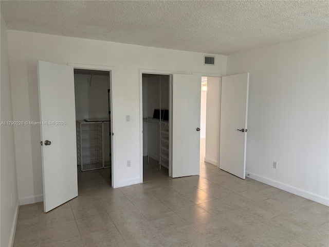 1420 Brickell Bay Dr Unit 103A1, Miami, FL 33131 - unfurnished bedroom with a closet, visible vents, a textured ceiling, and baseboards