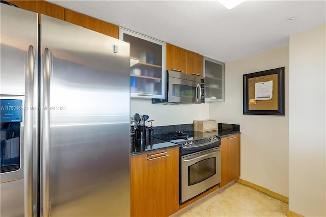 1800 N Bayshore Dr Unit 509, Miami, FL 33132 - kitchen with appliances with stainless steel finishes, brown cabinets, dark stone counters, and glass insert cabinets