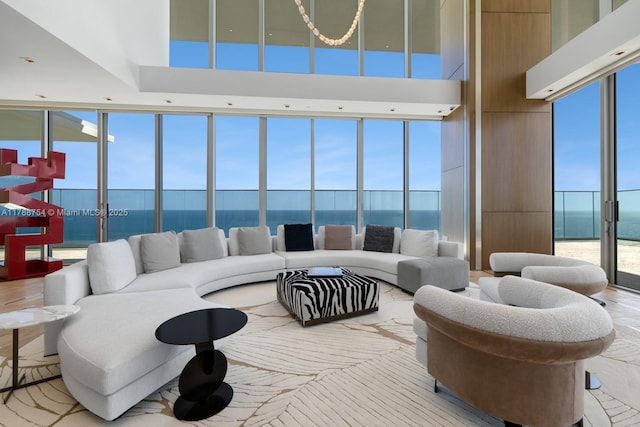 living room with a water view, a wall of windows, and a towering ceiling