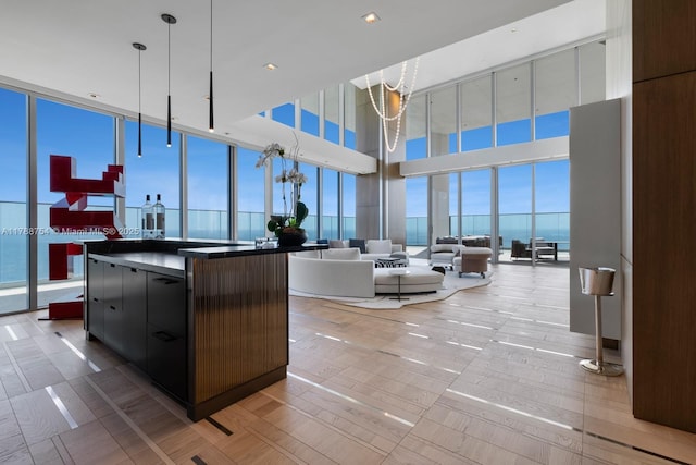 interior space with a wall of windows, a towering ceiling, dark countertops, modern cabinets, and open floor plan