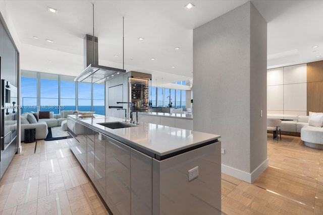 kitchen featuring open floor plan, a sink, a large island with sink, and modern cabinets