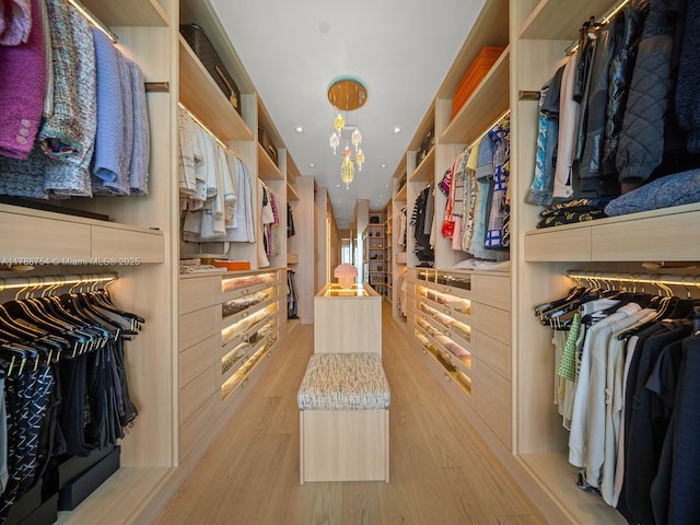 spacious closet featuring a chandelier and light wood-type flooring