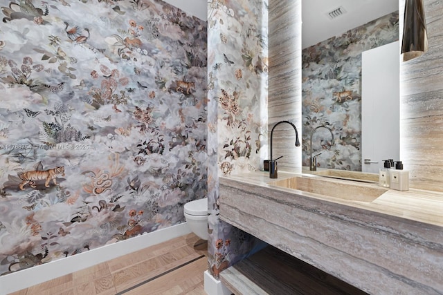 bathroom with visible vents, vanity, toilet, and wallpapered walls