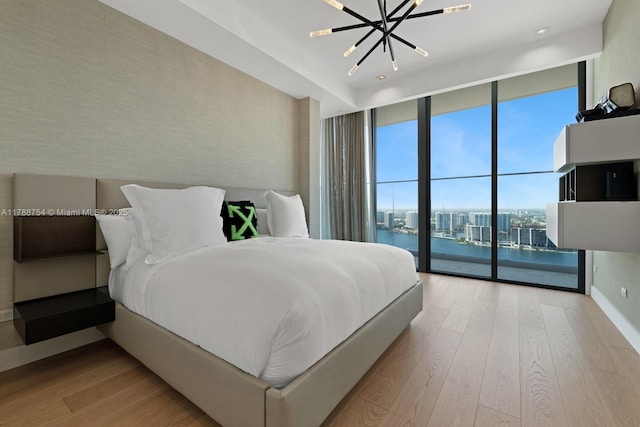 bedroom featuring wood finished floors, access to outside, expansive windows, and a chandelier