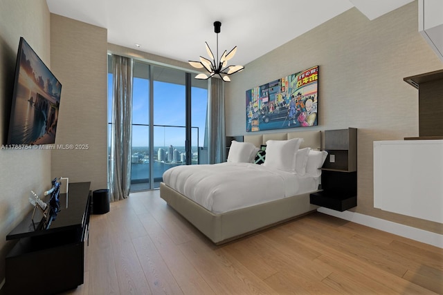 bedroom featuring an inviting chandelier, baseboards, and wood finished floors