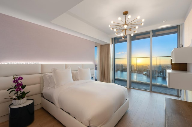 bedroom featuring access to outside, a wall of windows, an inviting chandelier, and wood finished floors