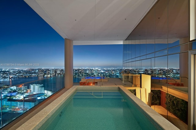 pool at night featuring a view of city lights