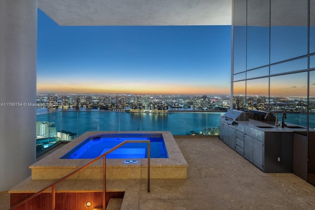 view of swimming pool with area for grilling, a view of city, an in ground hot tub, and a sink