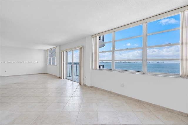 11930 N Bayshore Dr Unit 1007, North Miami, FL 33181 - unfurnished room with light tile patterned floors, a textured ceiling, a water view, and baseboards