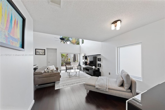 living room with visible vents, a ceiling fan, a textured ceiling, and dark wood finished floors