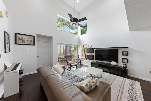 living area featuring a ceiling fan, baseboards, dark wood-style floors, and high vaulted ceiling