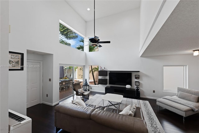 living room featuring a ceiling fan, baseboards, recessed lighting, a towering ceiling, and dark wood-style floors