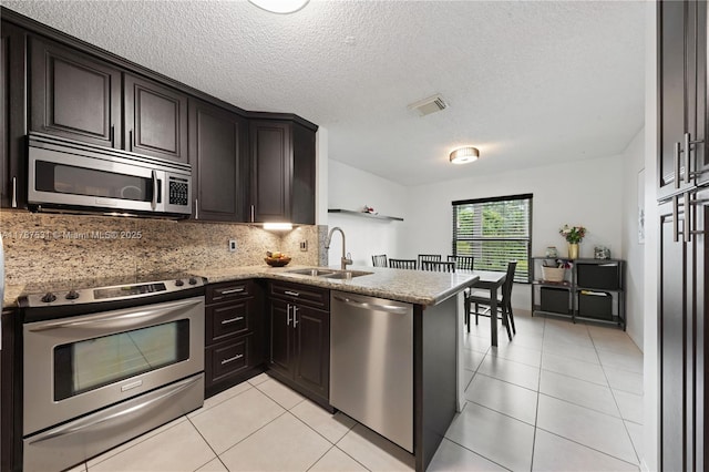 kitchen with a sink, appliances with stainless steel finishes, decorative backsplash, and light tile patterned floors
