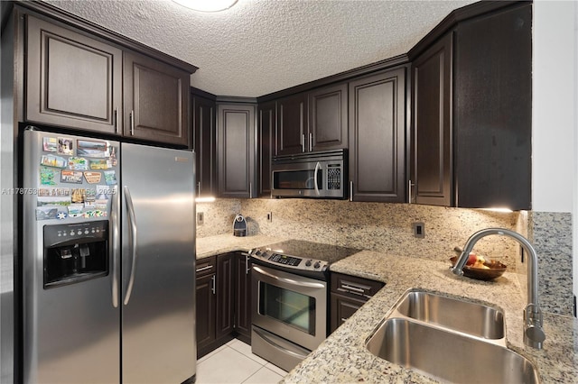 kitchen featuring a sink, light stone counters, light tile patterned floors, and stainless steel appliances