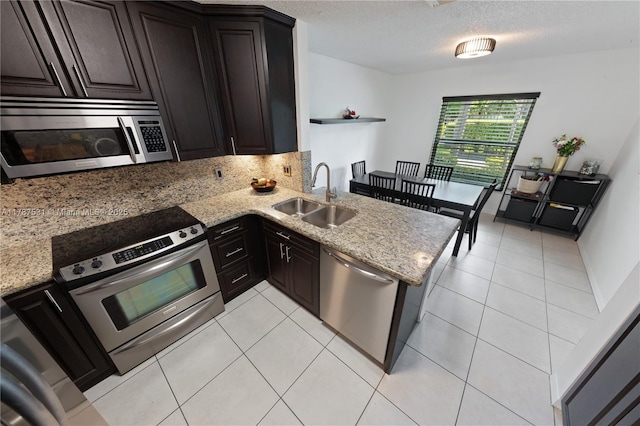 kitchen featuring stainless steel appliances, light stone countertops, light tile patterned floors, and a sink