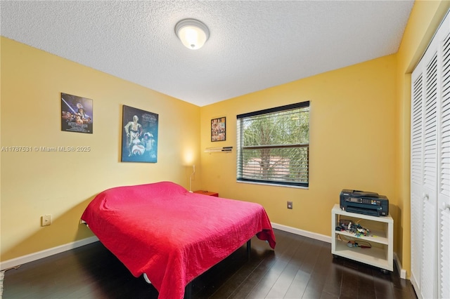bedroom with baseboards, a textured ceiling, wood-type flooring, and a closet