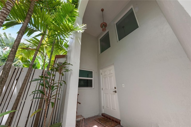 entrance to property featuring stucco siding and fence