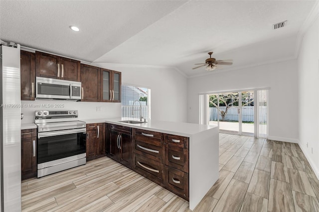 kitchen featuring stainless steel appliances, ceiling fan, visible vents, ornamental molding, and lofted ceiling