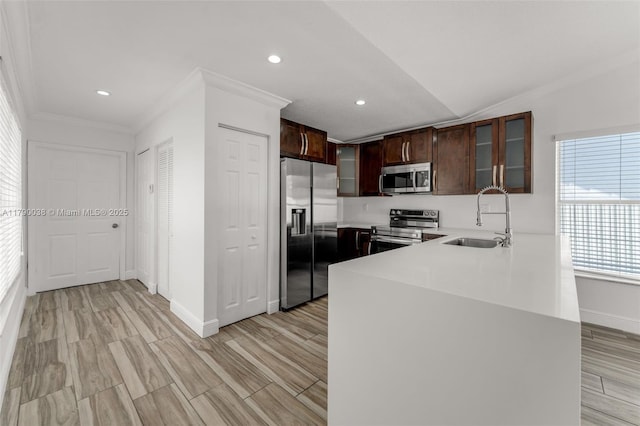 kitchen featuring recessed lighting, a sink, stainless steel appliances, baseboards, and ornamental molding