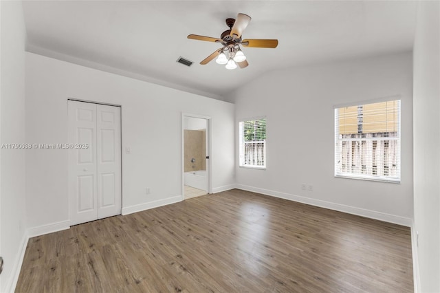 unfurnished bedroom featuring wood finished floors, connected bathroom, vaulted ceiling, and baseboards