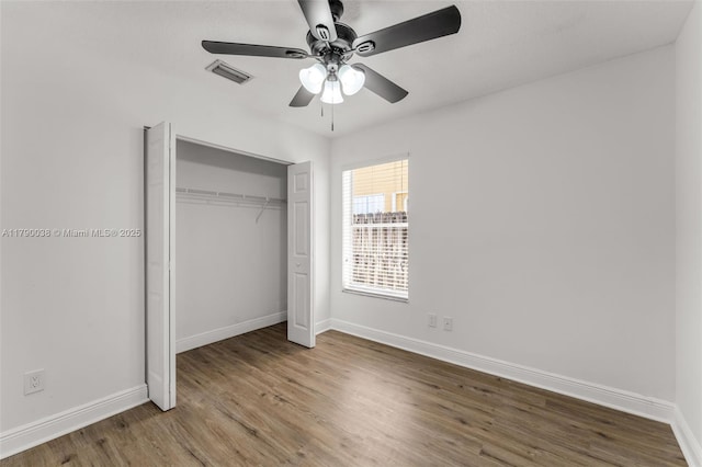 unfurnished bedroom with a closet, a ceiling fan, visible vents, baseboards, and wood finished floors