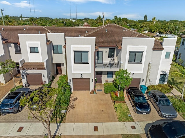 21364 NE 2nd Ct, Miami, FL 33179 - townhome / multi-family property featuring a balcony, stucco siding, driveway, a tiled roof, and an attached garage