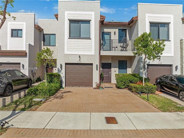 21364 NE 2nd Ct, Miami, FL 33179 - townhome / multi-family property with stucco siding, decorative driveway, a balcony, and a garage