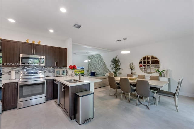 21364 NE 2nd Ct, Miami, FL 33179 - kitchen with a sink, stainless steel appliances, dark brown cabinetry, visible vents, and a peninsula