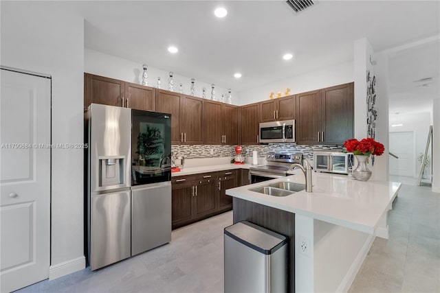 21364 NE 2nd Ct, Miami, FL 33179 - kitchen featuring a sink, stainless steel appliances, light countertops, a peninsula, and backsplash