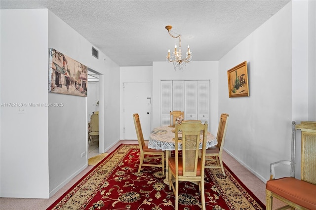 5601 Collins Ave Unit 1014, Miami Beach, FL 33140 - dining area featuring a textured ceiling, visible vents, baseboards, an inviting chandelier, and light carpet