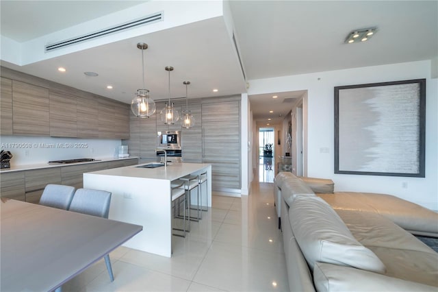 kitchen with stainless steel gas cooktop, a breakfast bar, light tile patterned floors, a sink, and modern cabinets