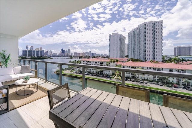 balcony with central AC unit, a water view, and a city view