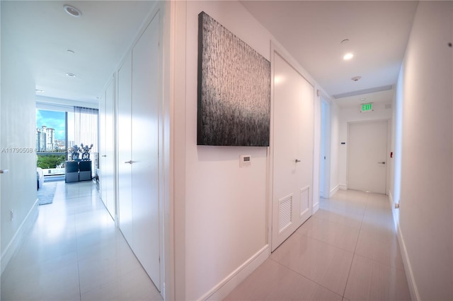 hall featuring baseboards, visible vents, and light tile patterned flooring