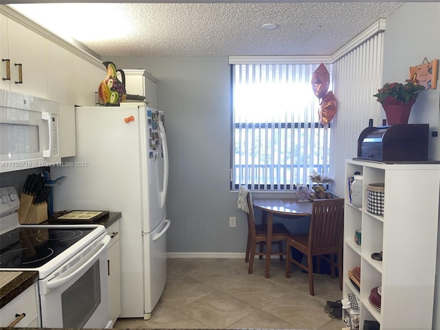 kitchen with dark countertops, a healthy amount of sunlight, white appliances, and white cabinetry