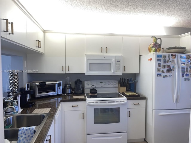 kitchen featuring a sink, white cabinetry, white appliances, dark countertops, and a textured ceiling