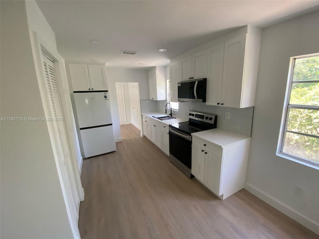 5028 NW 3rd Ave, Miami, FL 33127 - kitchen with stainless steel appliances, a sink, baseboards, light countertops, and light wood-type flooring
