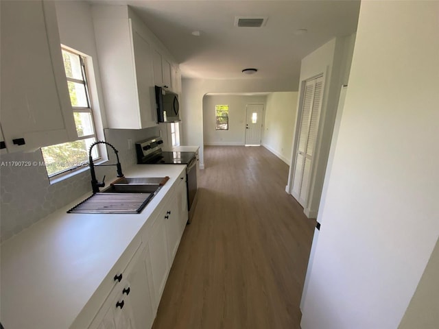 kitchen with white cabinets, black microwave, a sink, stainless steel range with electric stovetop, and visible vents