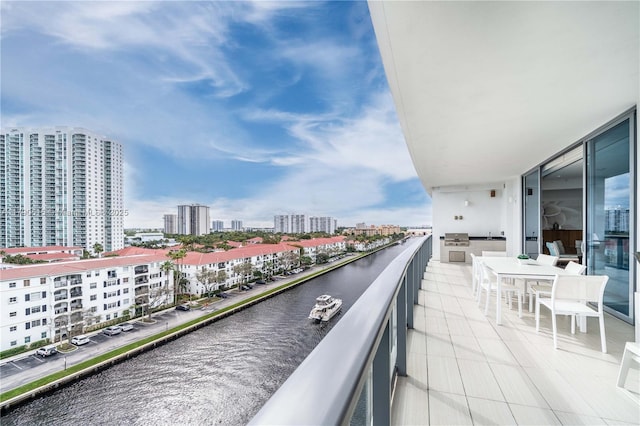 balcony featuring a view of city, outdoor dining space, and a water view